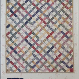 May include: A quilt pattern booklet titled American Pie by Miss Rosie's Quilt Co. RQC #33. The cover features a quilt with a repeating lattice design made of various floral fabric strips in red, blue, yellow, and green, set against a cream background.