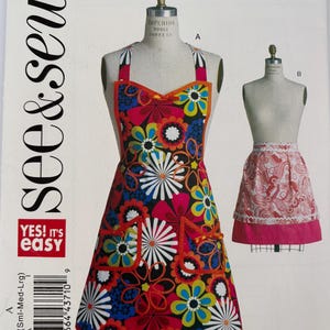 May include: A colorful floral print apron pattern with the text "see & sew" and "YES! It's easy". The apron features a vibrant design with red, blue, yellow, and white flowers. The pattern includes a full apron and a half apron.