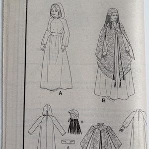 May include: A Simplicity 4443/0577 sewing pattern envelope featuring black and white line drawings of two costume variations. View A shows a hooded dress with a belt. View B displays a long dress with a patterned over-cape and a headpiece.
