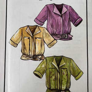 May include: A printed illustration titled In the Studio - 11 with Lois Ericson featuring three short-sleeved blouses with collars, front pockets, and belted waists. The blouses are rendered in purple, tan, and olive green with visible stitching details.
