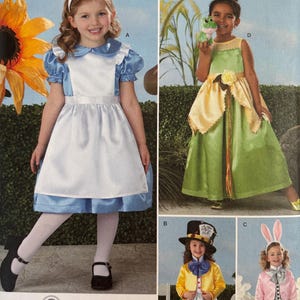 May include: Simplicity sewing pattern 2330, size A 3,4,5,6,7,8, featuring four costume designs: a blue and white dress, a green and yellow gown, a yellow jacket with a top hat, and a pink jacket with rabbit ears. The pattern envelope displays these outfits.