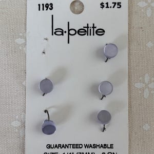 May include: A card of six lavender-colored stud earrings. The card reads "la-petite" and "GUARANTEED WASHABLE SIZE: 1/4" (7MM) - 6 ON."