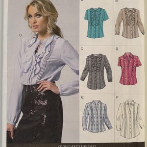 May include: A Vogue Patterns Easy sewing pattern envelope V8857 for blouses with various sleeve lengths, ruffle details, and button-front closures. The cover displays six variations labeled A through F, featuring different fabrics, patterns, and collar styles.