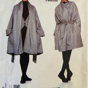 May include: A Vogue Patterns sewing pattern envelope for an Issey Miyake designer original coat, number 1836. The envelope displays two views of a grey, loose-fitting coat with wide sleeves, a tie waist, and a single button closure.