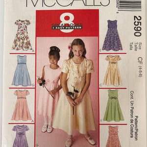 May include: McCall's 2590 sewing pattern envelope featuring illustrations of eight different dress variations for sizes 4-5-6. The cover displays two children wearing light-colored dresses and includes a barcode and product information text.
