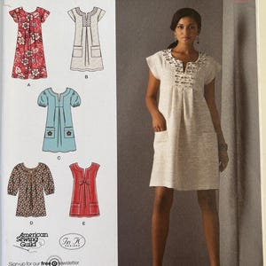 May include: Simplicity sewing pattern 2702 featuring various dress designs. The pattern includes options with short sleeves, pockets, and decorative details. The image also shows a woman wearing a light-colored dress with embellishments.