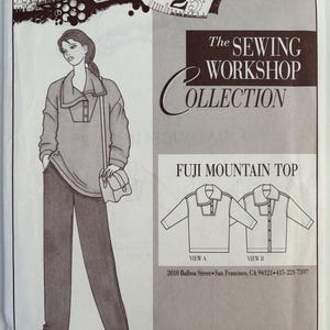 May include: A sewing pattern envelope for The Sewing Workshop Collection Fuji Mountain Top. The front features a line drawing of a person wearing a long-sleeved top with a collar and buttons, plus two technical sketches labeled View A and View B.