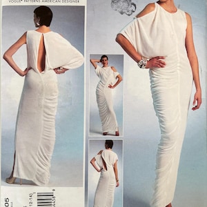 May include: A Lialia by Julia Alarcon Vogue Patterns American Designer sewing pattern envelope for a floor-length white dress. The dress features a cold-shoulder design, a draped bodice, a side-slit skirt, and an open back. Pattern number V1305.