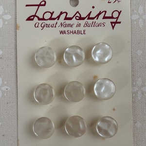 May include: A card of nine pearlescent, round buttons. The card reads "Lansing, A Great Name in Buttons, WASHABLE." The buttons are size 18-7/16 inches.