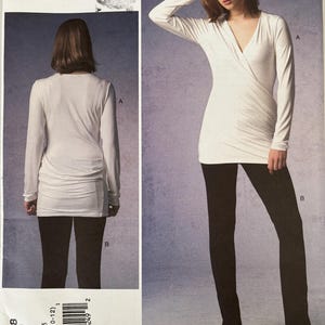 May include: A Donna Karan Collection Vogue Patterns sewing pattern envelope for a long-sleeve white wrap top and black pants. The front shows a white V-neck top with side ruching and black trousers. The back view shows the top's rear design. V1378.
