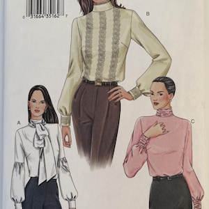 May include: Vogue Patterns sewing pattern 7604 featuring three blouse designs. The pattern includes sizes 20, 22, and 24. The blouses have long sleeves and various necklines, including a mock neck and a bow.