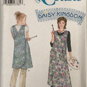 May include: Simplicity Crafts sewing pattern 5201 for a Daisy Kingdom apron. The pattern envelope displays two views of a floral print apron, one shorter and one longer, featuring a crossover design, pockets, and illustrations of painting tools.