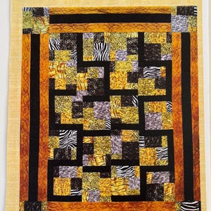 May include: A quilt pattern titled Follow The Leader by Pressed For Time Quiltworks. The cover features a rectangular quilt with a patchwork design of animal prints in black, gold, and white, framed by solid black and orange borders.