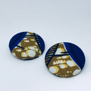 May include: A pair of round, fabric earrings with a blue, white, and brown geometric pattern.