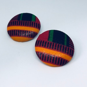 May include: A pair of round fabric earrings with a geometric pattern in red, orange, green, and black.