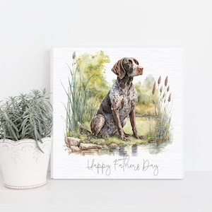 May include: A watercolour painting of a brown and white German Shorthaired Pointer dog sitting by a pond. The dog is looking to the right of the image. The background is a watercolour painting of green trees and tall grass. The text "Happy Father's Day" is written at the bottom of the image.