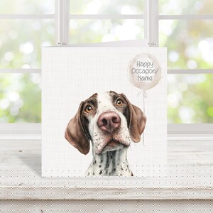 May include: A greeting card with a watercolour illustration of a dog's face, featuring brown and white markings. A balloon graphic with the text "Happy Occasion/ Name" floats above the dog's head. The card is set against a white background.