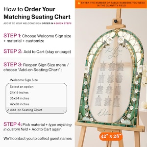 May include: An arched wedding seating chart sign featuring a stained glass-style border in shades of green and cream with white rose illustrations. The sign displays the text Find Your Seat and Welcome, with twelve numbered tables listed.