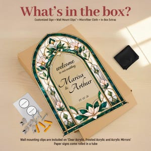 May include: An arched wedding sign featuring a stained glass-style border with green leaves and pink flowers. The center text reads welcome to our wedding Marisa & Arthur 05-02-26. Included are wall mount clips, a microfiber cloth, and in-box extras.