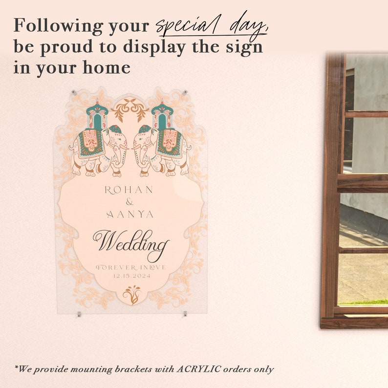 May include: A rectangular acrylic wedding sign featuring two illustrated elephants with teal and pink decorative saddles. The text reads: Following your special day, be proud to display the sign in your home, ROHAN & AANYA, Wedding, FOREVER IN LOVE, 12.15.2024.
