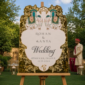 May include: A decorative wedding sign on a wooden easel featuring a white center with gold mirrored borders. The sign displays the text Rohan & Aanya, Wedding, Forever Inlove, and 12.15.2024, with illustrations of two elephants in teal and gold.