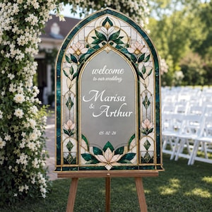 May include: An arched wedding welcome sign featuring a stained glass border with green and cream floral patterns. The center panel is gray with white text reading: welcome to our wedding, Marisa & Arthur, and the date 05.02.26.