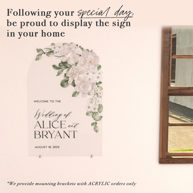 May include: An arched clear acrylic wedding sign featuring a floral illustration of white flowers and green leaves in the upper right corner. The text reads: WELCOME TO THE Wedding of ALICE and BRYANT AUGUST 18, 2023. The sign is mounted with small metal brackets.