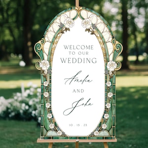 May include: An arched wedding welcome sign featuring a stained glass-style border in shades of green and gold with white rose illustrations. The centre text reads: WELCOME TO OUR WEDDING, Amelia AND John, 10.15.25. The sign is mounted on a wooden easel.