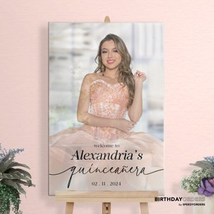 May include: A welcome sign for a quincea&ntilde;era, featuring a photo of the birthday girl in a pink dress. The sign reads "Welcome to Alexandria's Quincea&ntilde;era 02.11.2024".