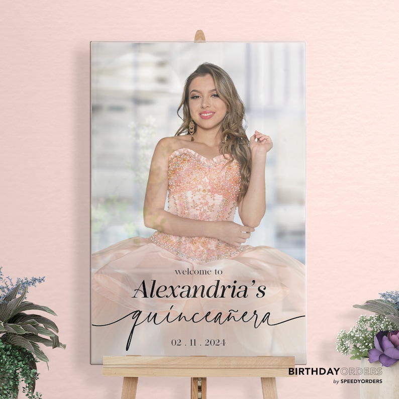 May include: A welcome sign for a quincea&ntilde;era, featuring a photo of the birthday girl in a pink dress. The sign reads "Welcome to Alexandria's Quincea&ntilde;era 02.11.2024".