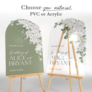 May include: Two arched wedding signs, one sage green and one clear acrylic, both featuring white floral illustrations and the text: Choose your material PVC or Acrylic, WELCOME TO THE Wedding of ALICE and BRYANT, AUGUST 18, 2023. Each sign is displayed on a wooden easel.