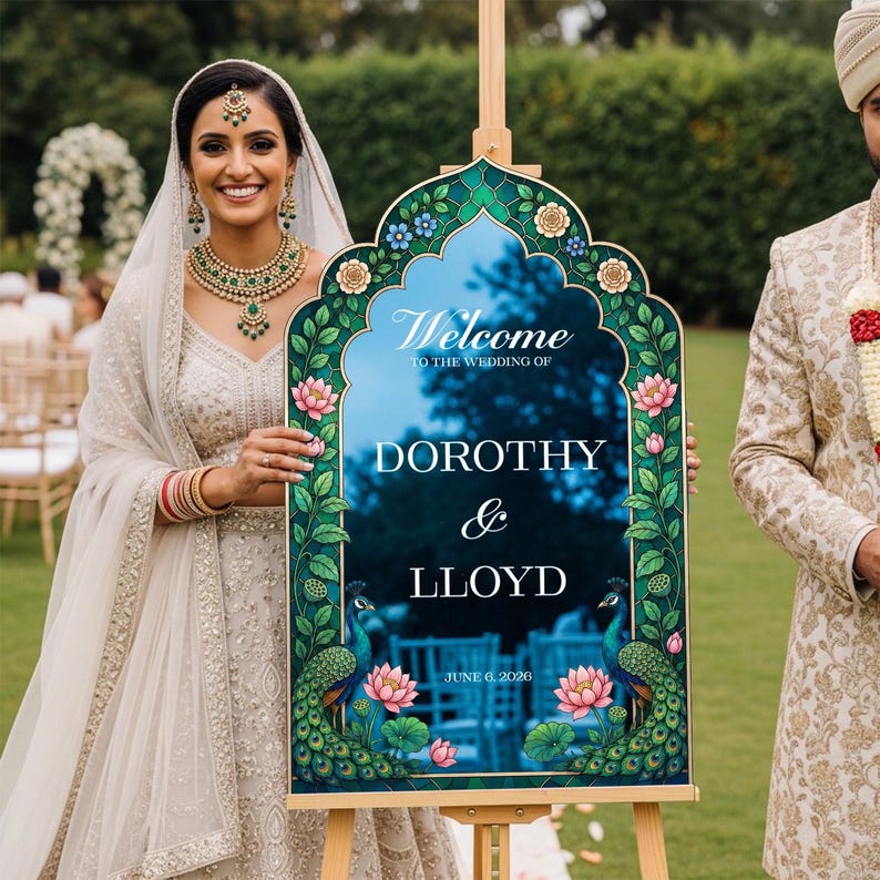 Op de afbeelding: Een boogvormig welkomstbord voor een bruiloft met een donkerblauw midden en witte tekst die Welcome to the wedding of Dorothy & Lloyd June 6, 2026 leest. De rand toont groene pauwenveren, roze lotusbloemen en blauwe florale accenten.
