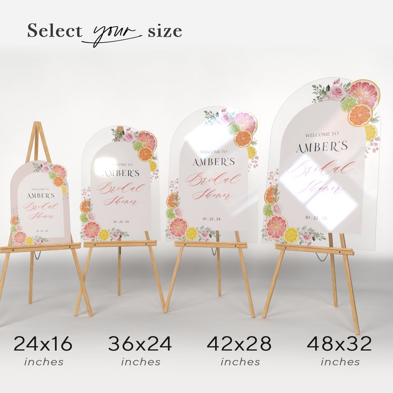 May include: Four clear acrylic signs with a rounded arch top, featuring a watercolour design of citrus fruit and flowers. The signs are on wooden easels and have the text "Welcome to Amber's Bridal Shower" with different sizes listed below each sign: 24x16 inches, 36x24 inches, 42x28 inches, and 48x32 inches.