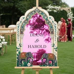 Peut inclure: Un panneau de bienvenue de mariage avec un cadre miroir rose en forme d'arche, des bordures florales, deux &eacute;l&eacute;phants illustr&eacute;s avec des couvertures rouges et dor&eacute;es, et le texte Welcome to the wedding Diane & Harold March 6, 2026 sur un chevalet.