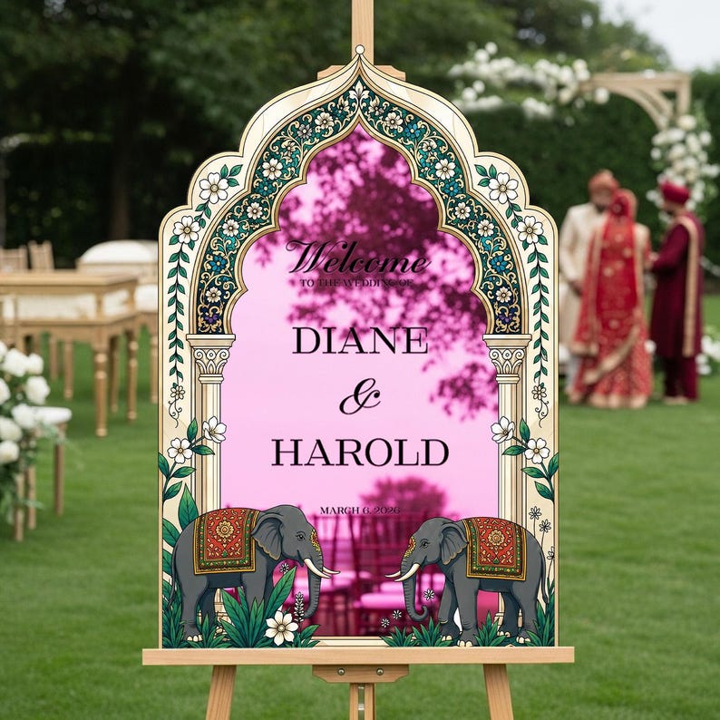 Peut inclure: Un panneau de bienvenue de mariage avec un cadre miroir rose en forme d'arche, des bordures florales, deux &eacute;l&eacute;phants illustr&eacute;s avec des couvertures rouges et dor&eacute;es, et le texte Welcome to the wedding Diane & Harold March 6, 2026 sur un chevalet.