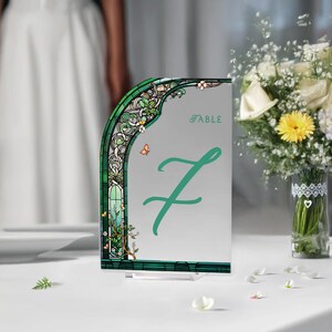 May include: A green and white table number card with a stained glass design and the word "TABLE" and the number "7" in green.