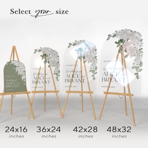 May include: Four arched wedding signs on wooden easels, ranging from 24x16 to 48x32 inches. The signs feature white floral arrangements and text reading Welcome to the Wedding of Alice and Bryant August 18, 2023. One sign is sage green, three are clear.