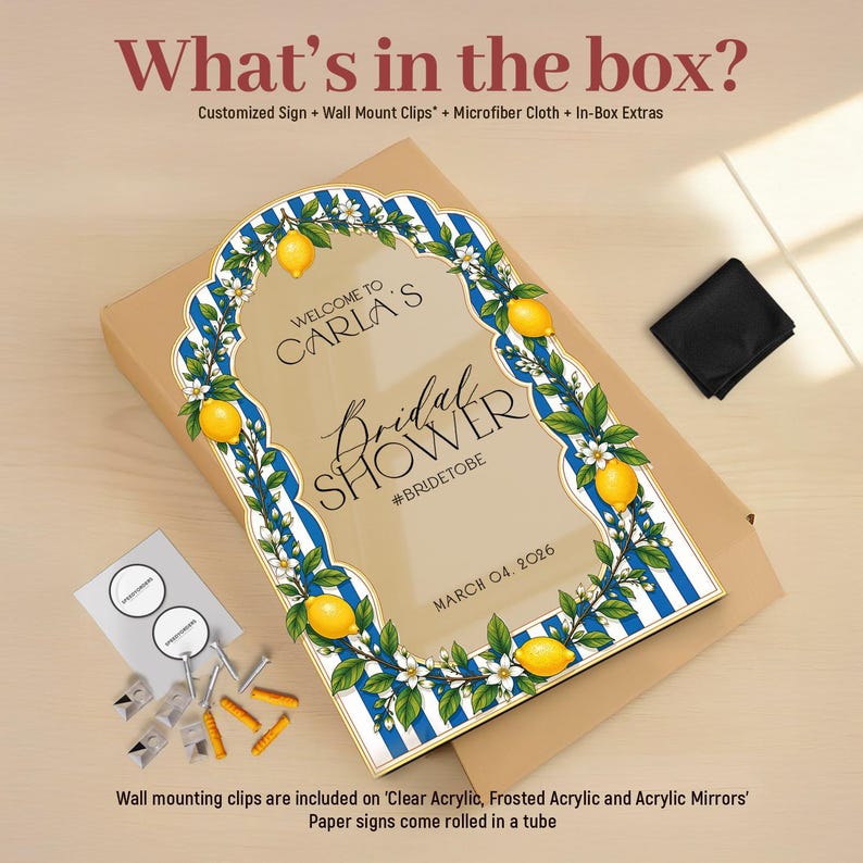 May include: A rectangular sign with a blue and white striped border, decorated with yellow lemons and white blossoms. The text reads: Welcome to Carla's Bridal Shower #bridetobe March 04, 2026. Included are wall mount clips, a black cloth, and hardware.
