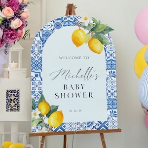 May include: Welcome to Michelle's Baby Shower sign with a blue and white tile pattern and lemons. The date is 10.22.24.