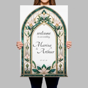 May include: A rectangular wedding welcome sign featuring an arched stained glass border in shades of emerald green and cream with floral motifs. The center text reads: welcome to our wedding, Marisa & Arthur, and the date 05.02.26 in black script.