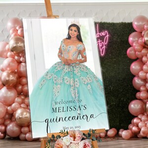 May include: A welcome sign for a quincea&ntilde;era celebration. The sign features a photo of a young woman in a light blue and white dress with a crown on her head. The text on the sign reads "Welcome to Melissa's Quincea&ntilde;era" and "May 20, 2023".