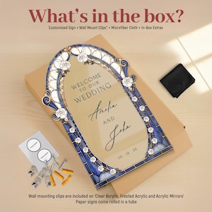 May include: A wedding sign with a stained glass design, featuring the names "Amelia and John" and the date "10.15.25". The sign is framed in blue and white, with floral accents. The text "WELCOME TO OUR WEDDING" is at the top.