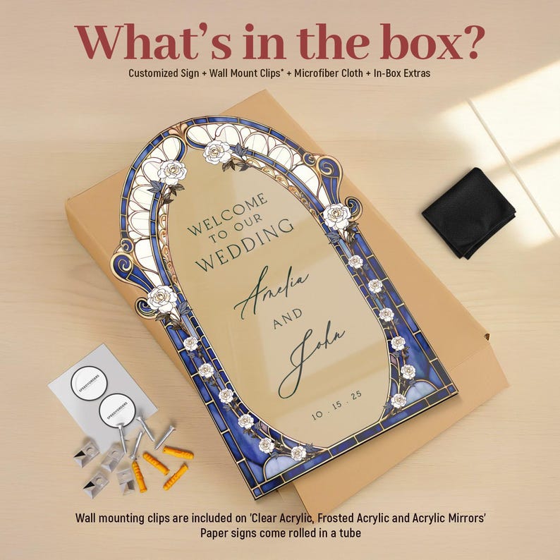 May include: A wedding sign with a stained glass design, featuring the names "Amelia and John" and the date "10.15.25". The sign is framed in blue and white, with floral accents. The text "WELCOME TO OUR WEDDING" is at the top.