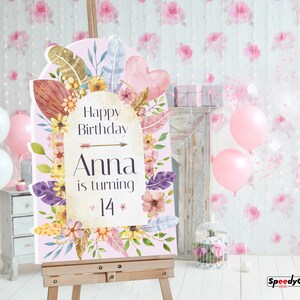 May include: A rectangular birthday sign with an arched top, featuring a light pink background decorated with watercolor flowers, leaves, and feathers. The text reads: Happy Birthday Anna is turning 14, accented by a small arrow and heart icons.
