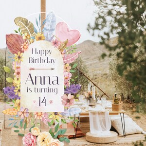 May include: An arched acrylic birthday sign featuring watercolor illustrations of flowers, feathers, and a heart. The text reads Happy Birthday, Anna is turning 14, with a small arrow graphic. The sign is displayed on a wooden easel stand.