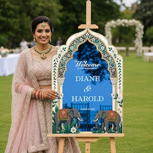 Peut inclure: Un panneau de bienvenue de mariage avec un centre arqu&eacute; bleu et du texte blanc indiquant Welcome to the wedding of Diane & Harold March 6, 2026. Le cadre pr&eacute;sente une bordure florale d&eacute;corative et deux &eacute;l&eacute;phants gris avec des couvertures rouges et dor&eacute;es.