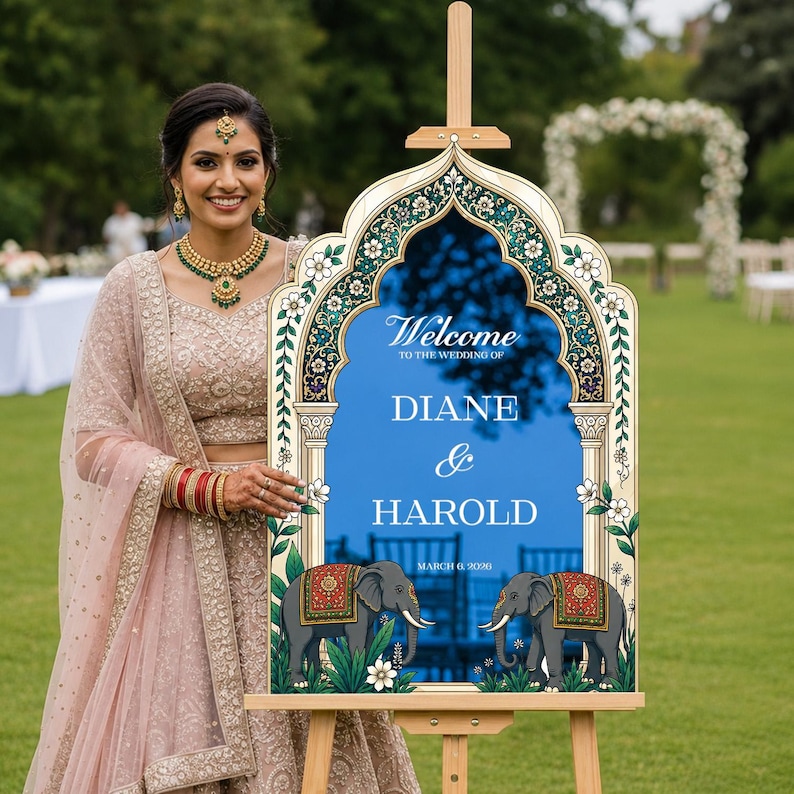 Peut inclure: Un panneau de bienvenue de mariage avec un centre arqu&eacute; bleu et du texte blanc indiquant Welcome to the wedding of Diane & Harold March 6, 2026. Le cadre pr&eacute;sente une bordure florale d&eacute;corative et deux &eacute;l&eacute;phants gris avec des couvertures rouges et dor&eacute;es.
