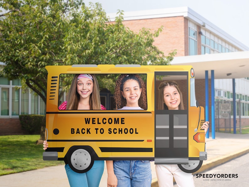 May include: Three girls pose for a photo holding a yellow cardboard cutout of a school bus. The bus has the words "Welcome Back to School" on the front.