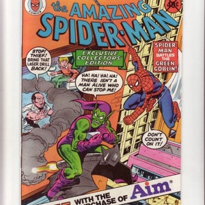 Puede incluir: Una portada de cómic que muestra a Spider-Man luchando contra el Duende Verde. La portada es roja, verde y amarilla con el texto "The Amazing Spider-Man" en letras grandes y en negrita. La portada también incluye el texto "Exclusive Collectors Edition" y "Free with the purchase of Aim".