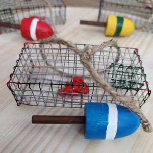 May include: A set of three wire lobster trap ornaments with red, yellow and blue buoys. Each trap is decorated with a small lobster figurine and a piece of twine.